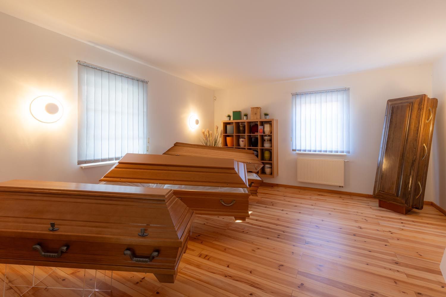 Holzzimmer mit zwei sargförmigen Tischen, warmem Licht, Fenstern, Regalen und einem Standspiegel