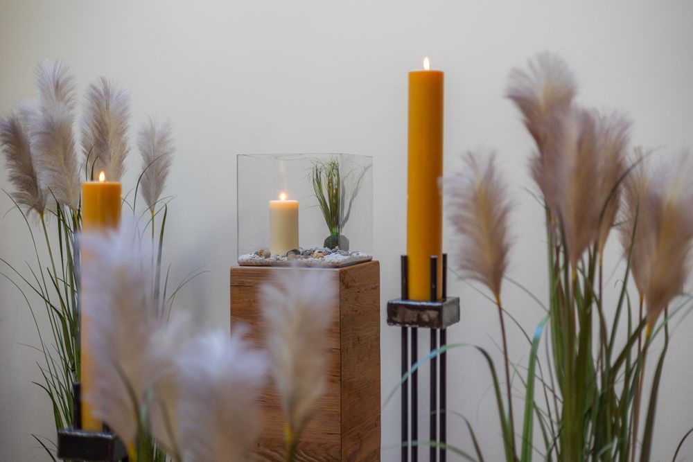 Kerzen auf Sockeln mit Pampasgras in einem minimalistischen Indoor-Arrangement