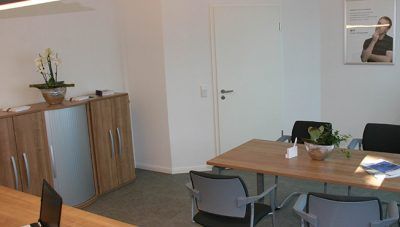Bürobesprechungsraum mit Holzschränken, Tisch, Stühlen und einem Wandfoto einer Person