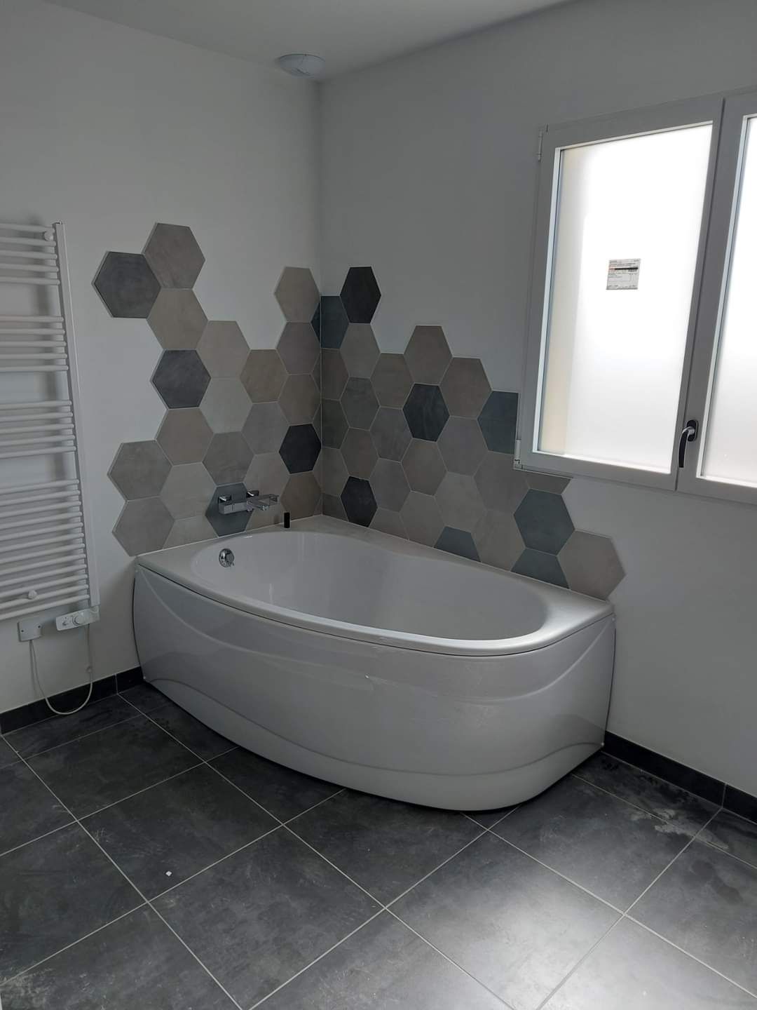 Carrelage noir au sol sous baignoire blanche