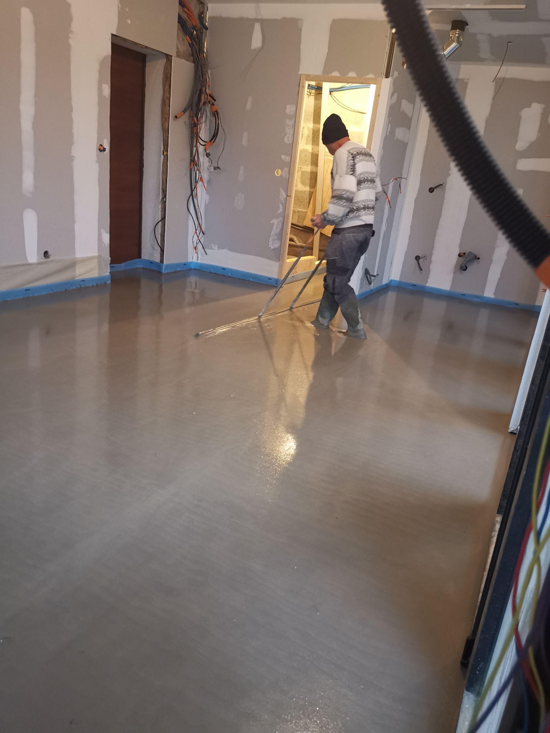 Artisan en train de lisser une chape en béton