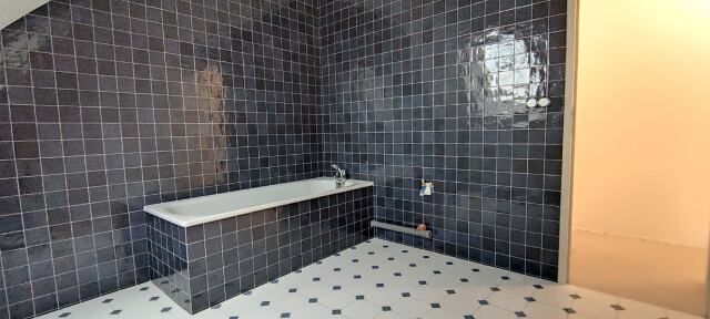 Salle de bain en carrelage noir au mur