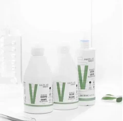 Hay tres botellas de productos para el cabello sobre una mesa.