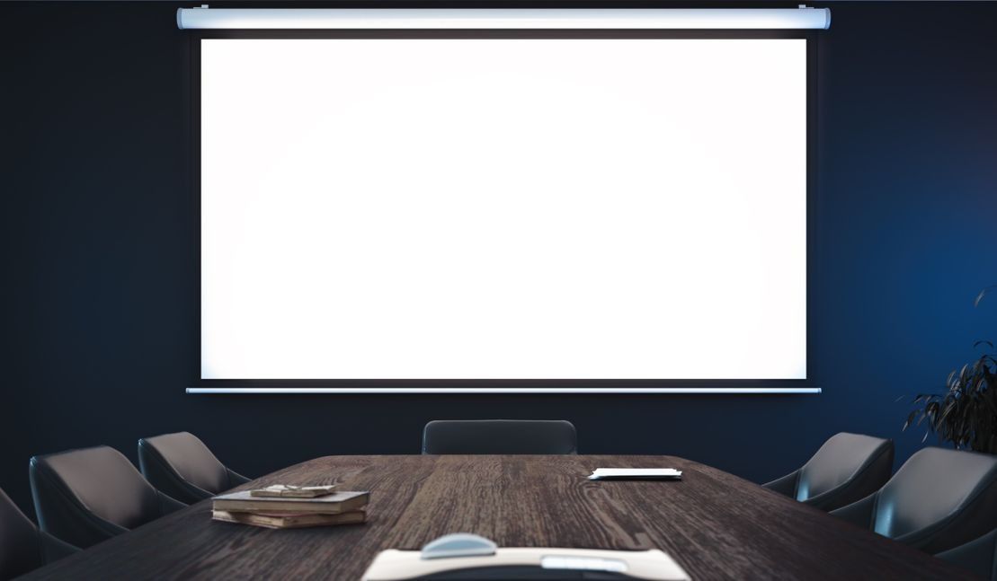 Una sala de conferencias con una pantalla de proyector y una mesa de madera.