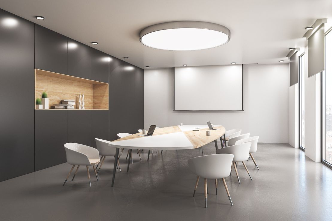 Una sala de conferencias con una mesa larga y sillas y una pantalla de proyección.