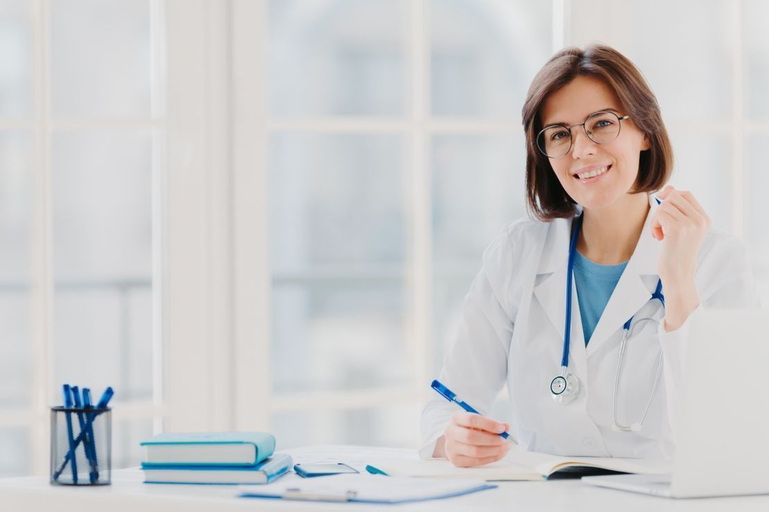 Una doctora está sentada en un escritorio con un bolígrafo en la mano.