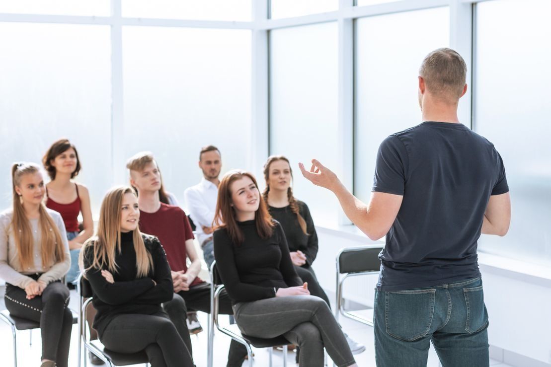 Un hombre está dando una presentación a un grupo de personas sentadas en sillas.