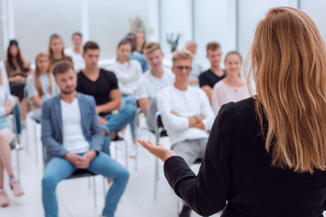 Una mujer está dando una presentación a un grupo de personas sentadas en sillas.