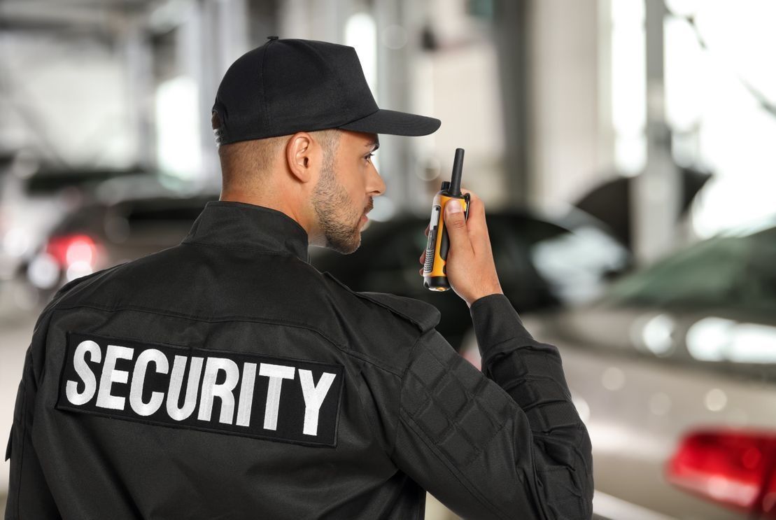Un guardia de seguridad está usando un walkie talkie en un estacionamiento.