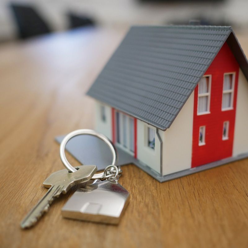 Una casa modelo y llaves sobre una mesa de madera