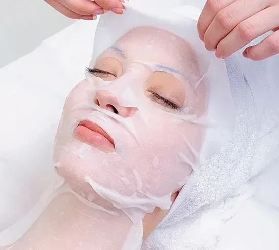 Persona con los ojos cerrados, recibiendo una mascarilla facial en un spa.