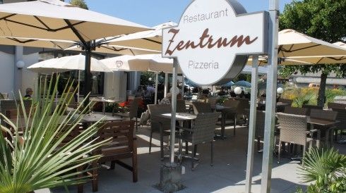 Terrasse mit Stühlen, Tischen und Sonnenschirmen bei Zentrum Restaurant-Pizzeria