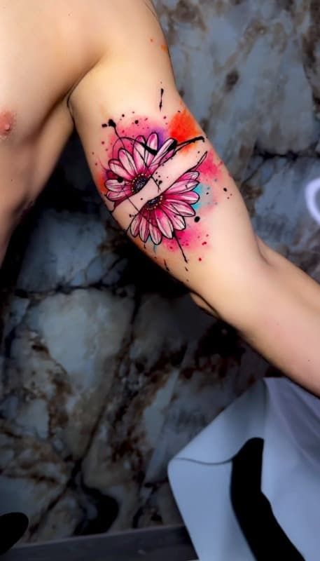 Brazo con tatuaje de mariposa rosa y negra cerca del codo.