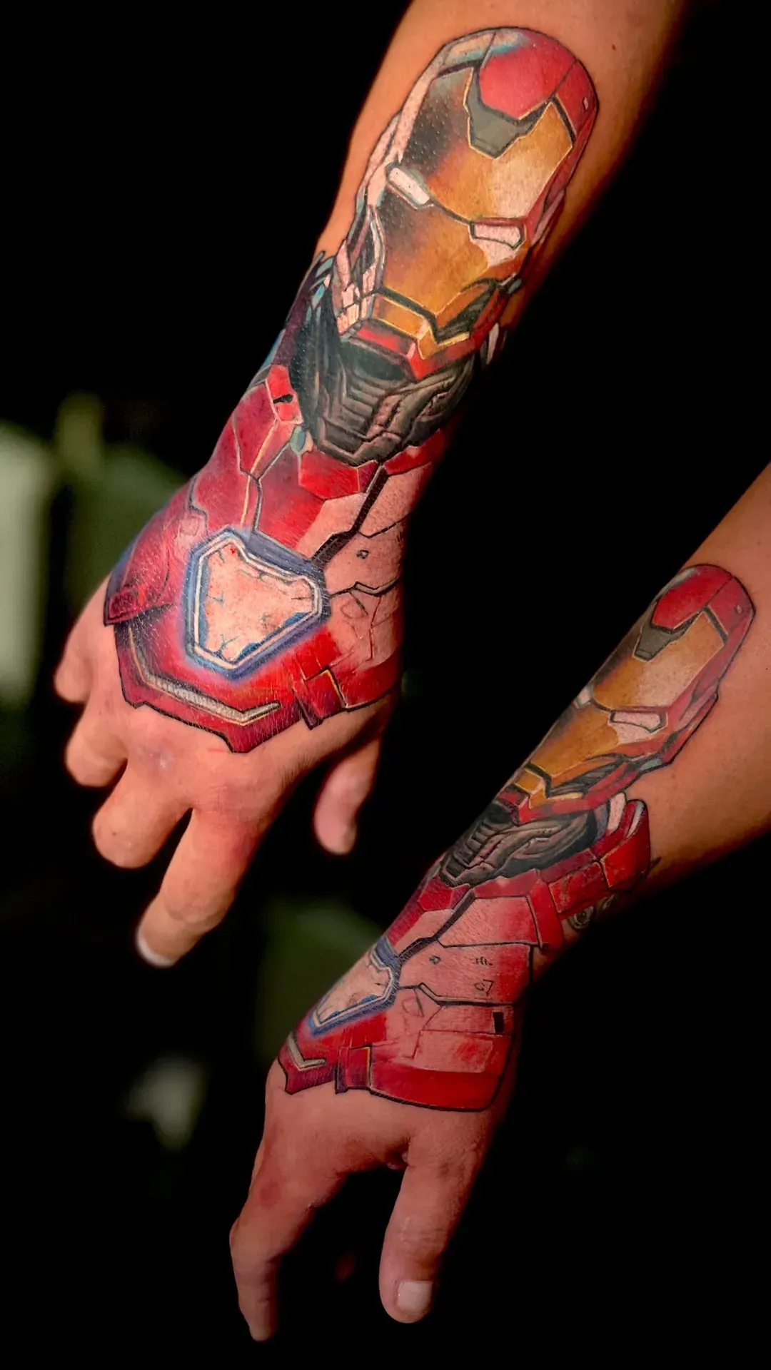 Tatuajes de armadura de Iron Man en ambos antebrazos y manos, detalles en rojo y dorado.