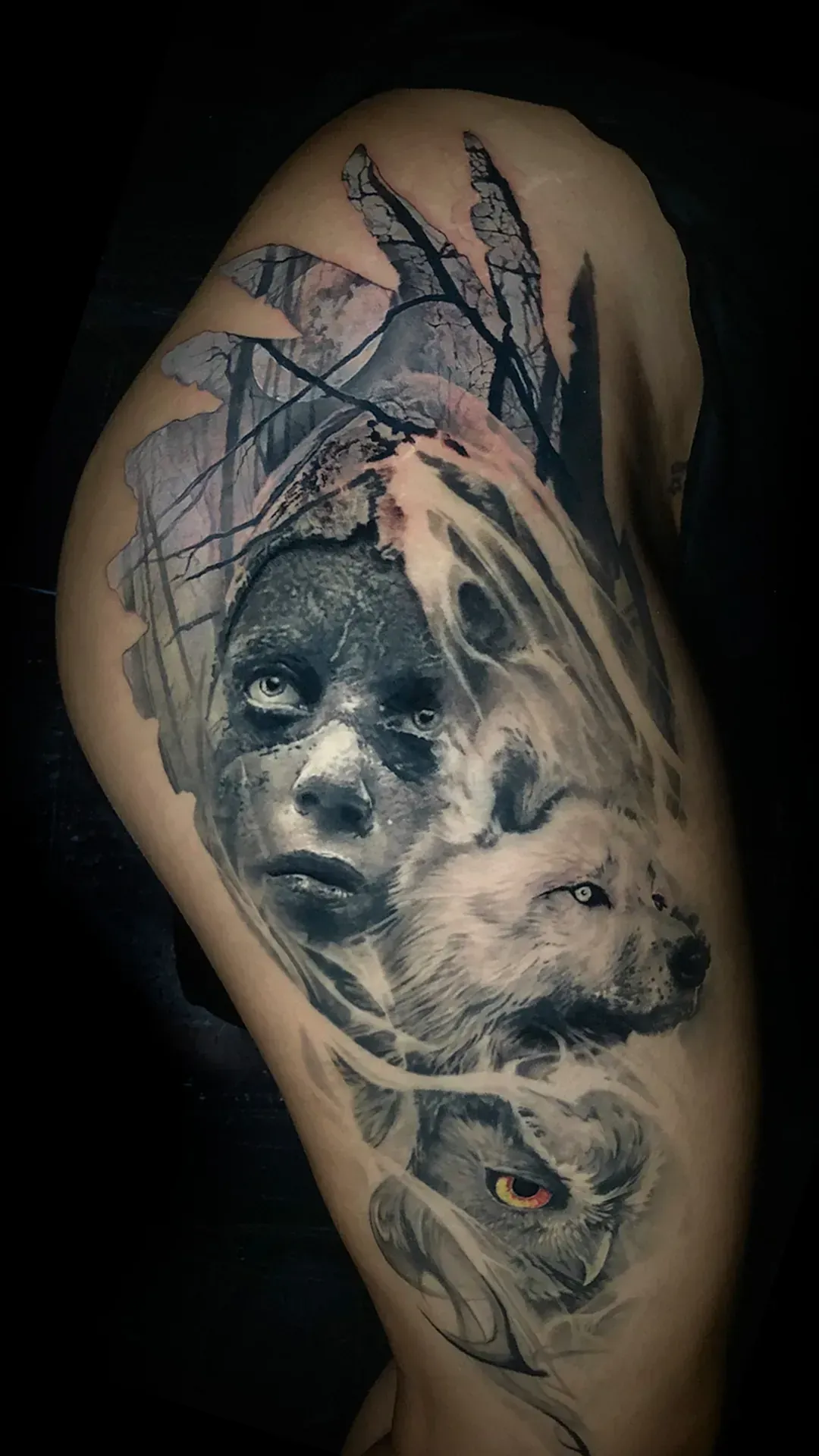 Tatuaje de una persona con marcas faciales oscuras y un lobo, con una línea de árboles al fondo.