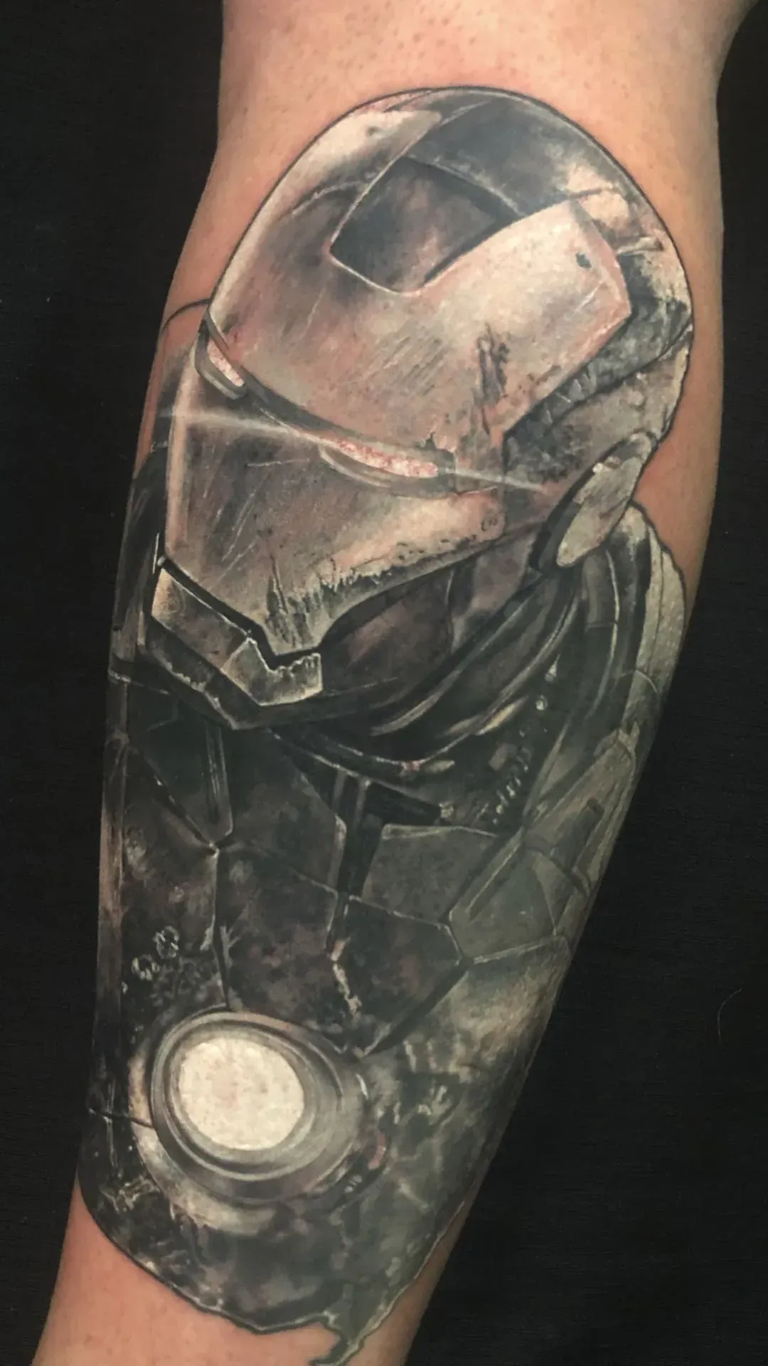 Tatuaje de la armadura de Iron Man en el antebrazo de una persona, realizado en color negro y gris.