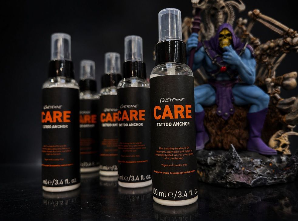 Cuatro botellas de spray negras con la etiqueta CARE sobre una mesa, junto a una figurita morada.