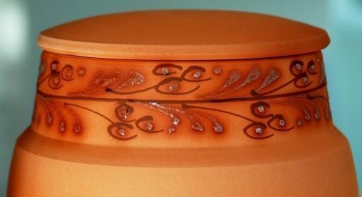 Eine Nahaufnahme einer orangefarbenen Vase mit einem Blumenmuster darauf