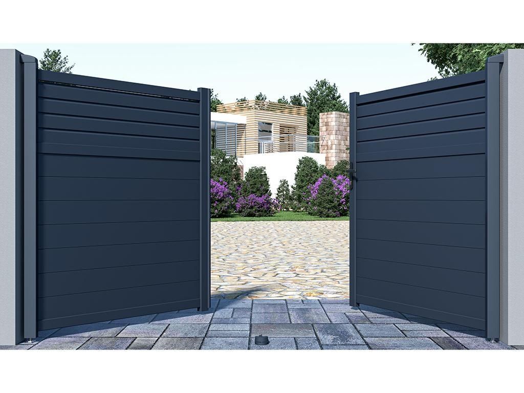 Un automóvil gris ingresa a un camino de entrada a través de una puerta moderna con listones horizontales.