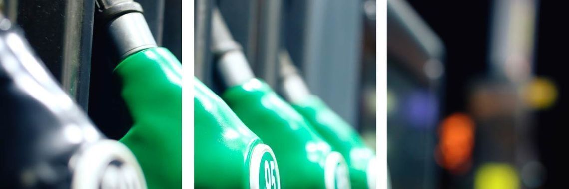 Una fila de surtidores de gasolina verdes están alineados en una gasolinera.