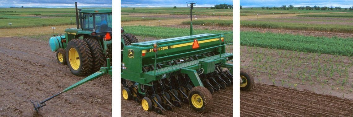 Un tractor está arando un campo con una sembradora acoplada a él.