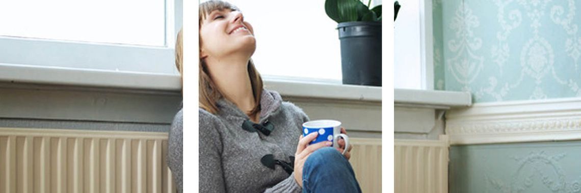 Una mujer está sentada en el suelo sosteniendo una taza de café.