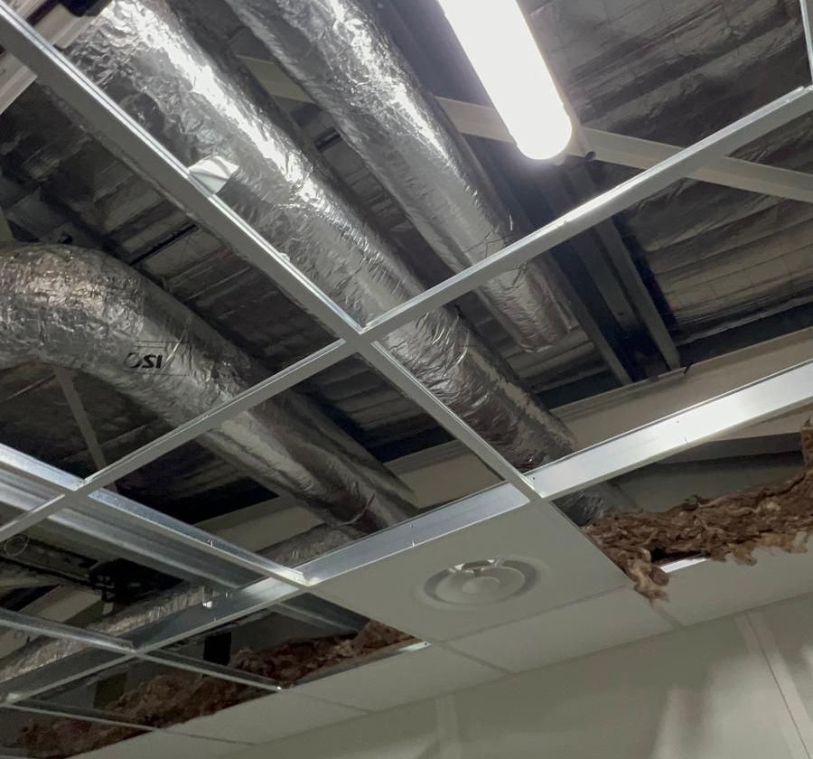 Ossature métallique avec panneaux manquants laissant apparaître des conduits avec isolant.