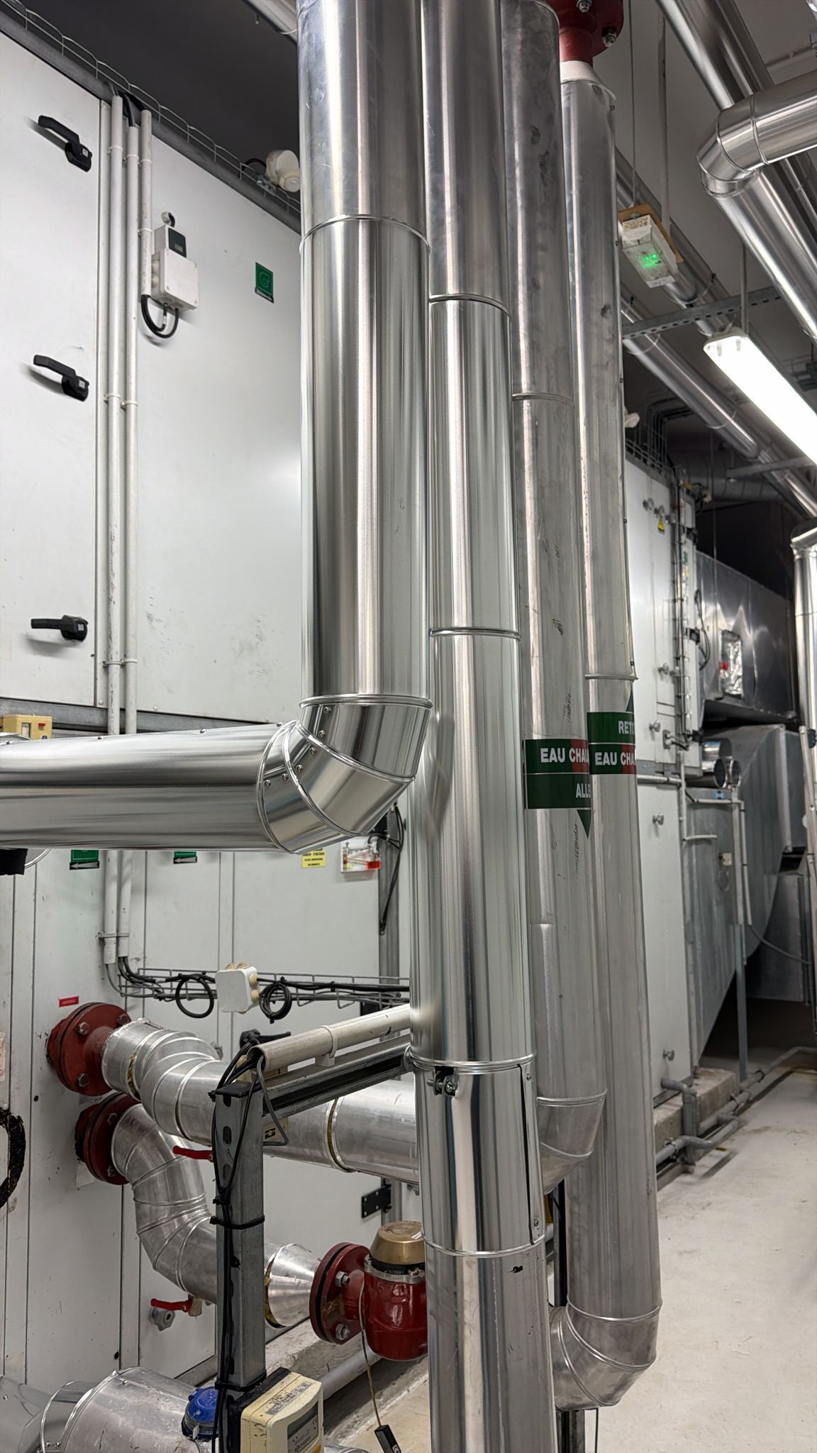 Tuyauterie et équipements industriels avec isolation argentée et vanne rouge.