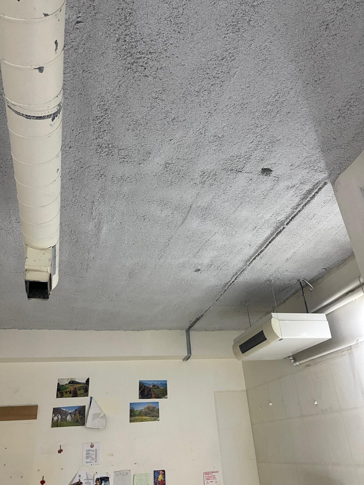 Plafond blanc texturé, conduits de ventilation et unités de climatisation.