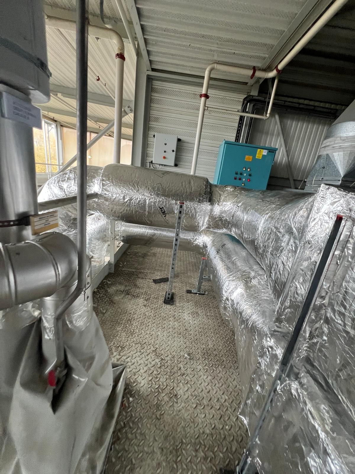 Conduits et tuyaux de CVC isolés avec du papier aluminium, dans un environnement industriel.