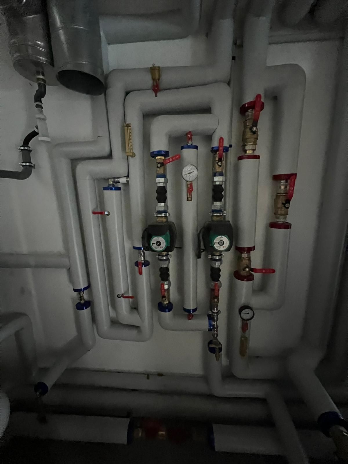 Système de tuyauterie avec tuyaux isolés, vannes et manomètres dans un local technique.