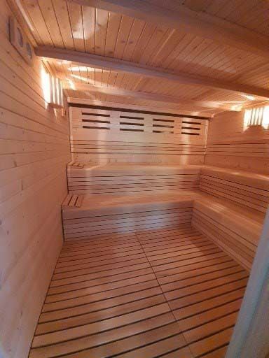 Interior de sauna de madera con bancos, suelo de listones y paneles de madera.