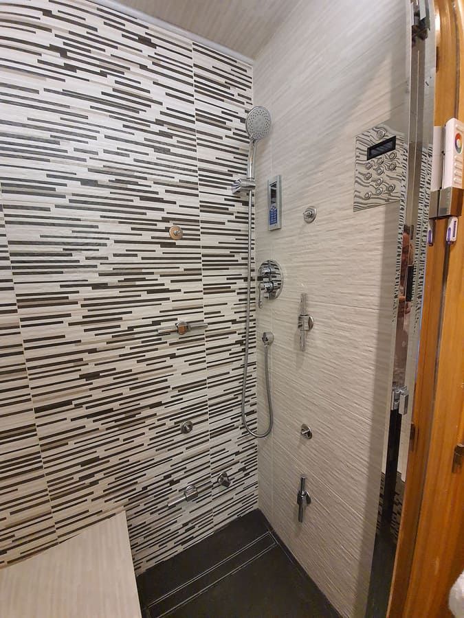 Ducha con múltiples cabezales y chorros corporales. Pared de azulejos.