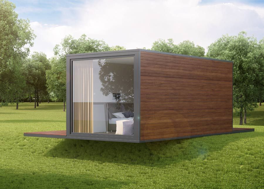 Cabaña moderna de color marrón y cristal sobre césped verde con árboles. Gran ventanal que parece un dormitorio.