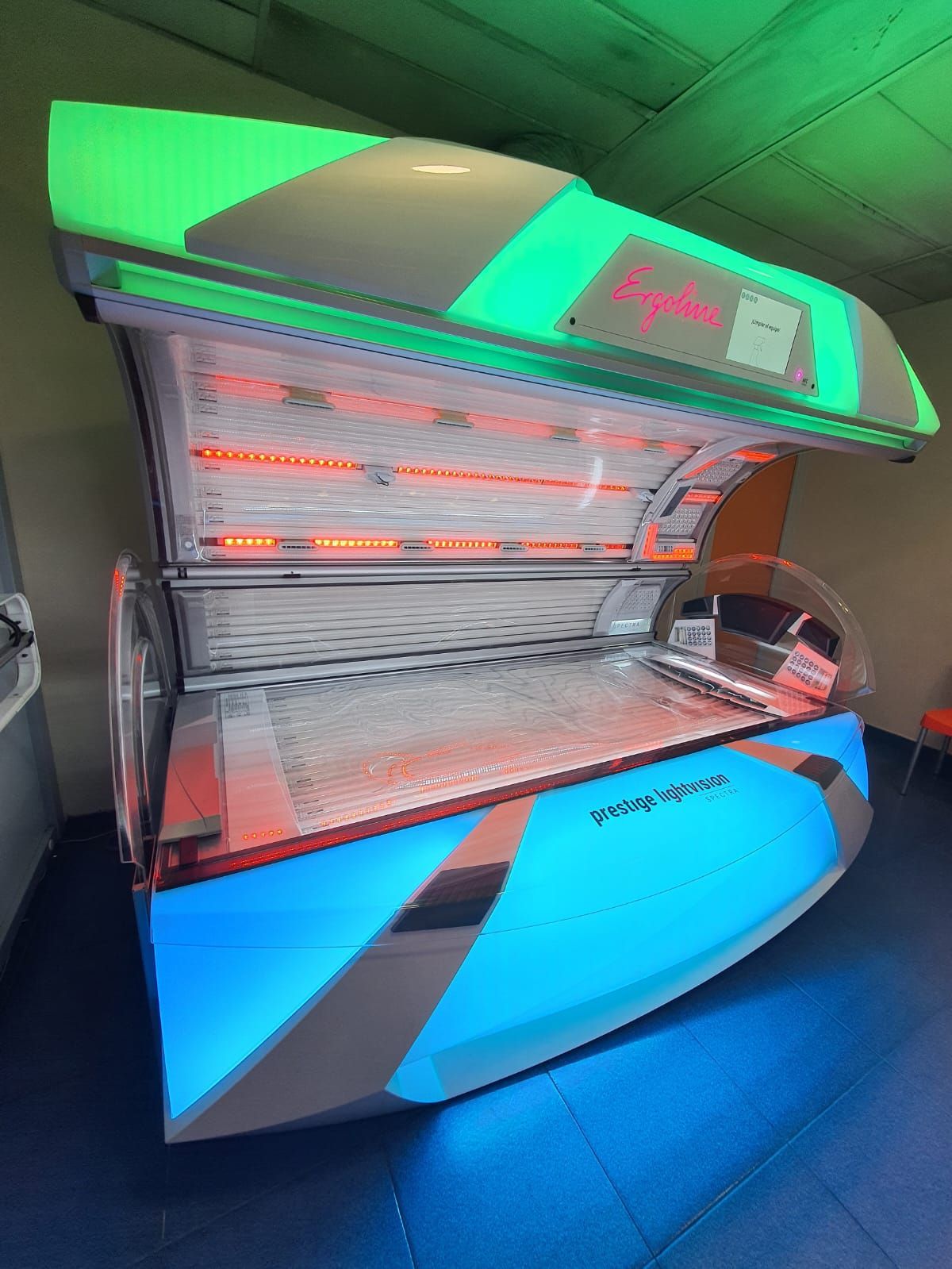 Una cama de bronceado con luces azules, naranjas y verdes.