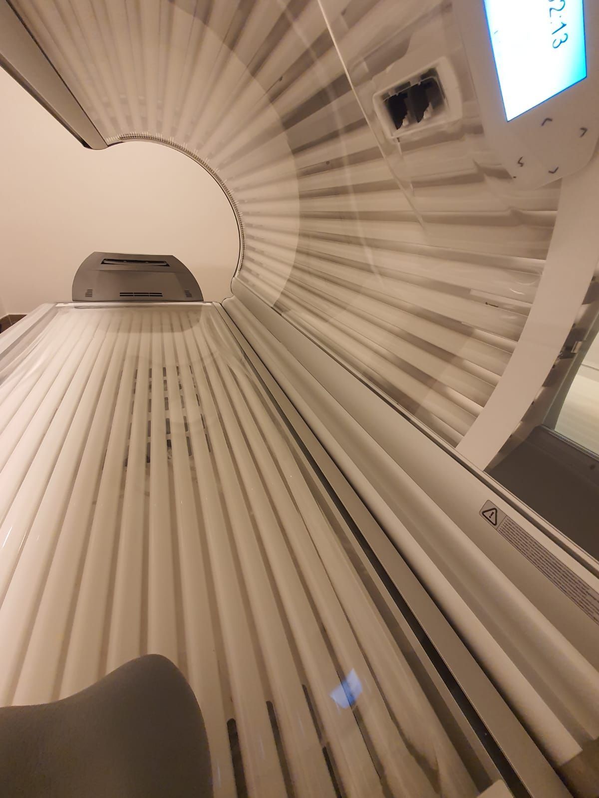 Vista interior de una cama de bronceado con paneles blancos y grises.