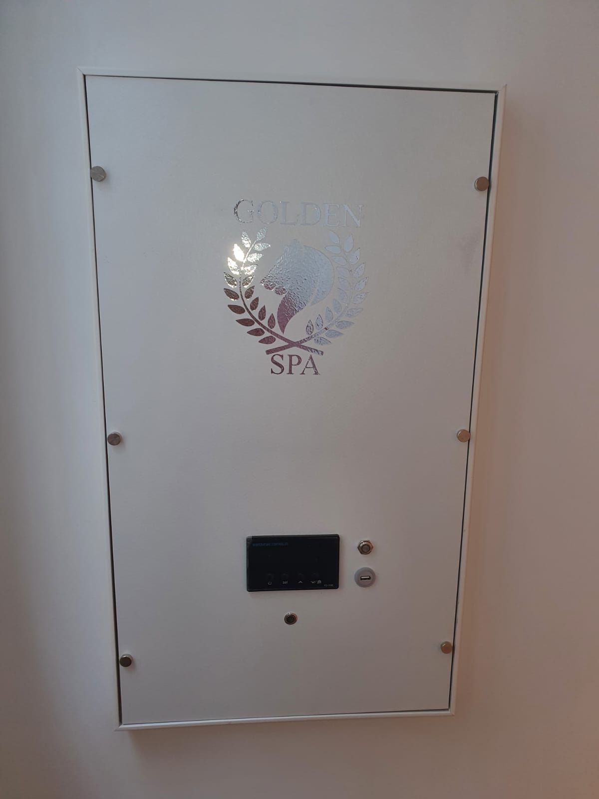 Panel de equipo de spa blanco con logotipo, panel de control y cerradura montado en una pared.