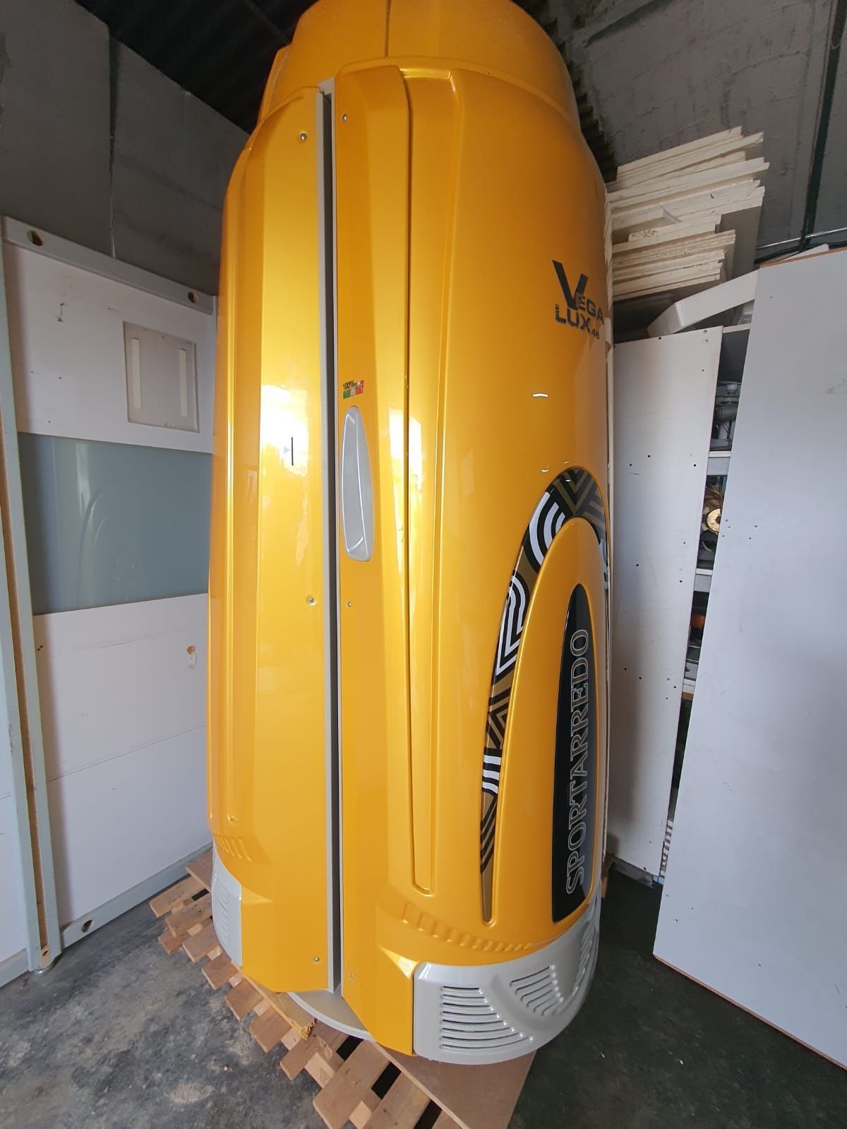 Cama de bronceado vertical de color amarillo con diseño de rayas de cebra, en interiores.