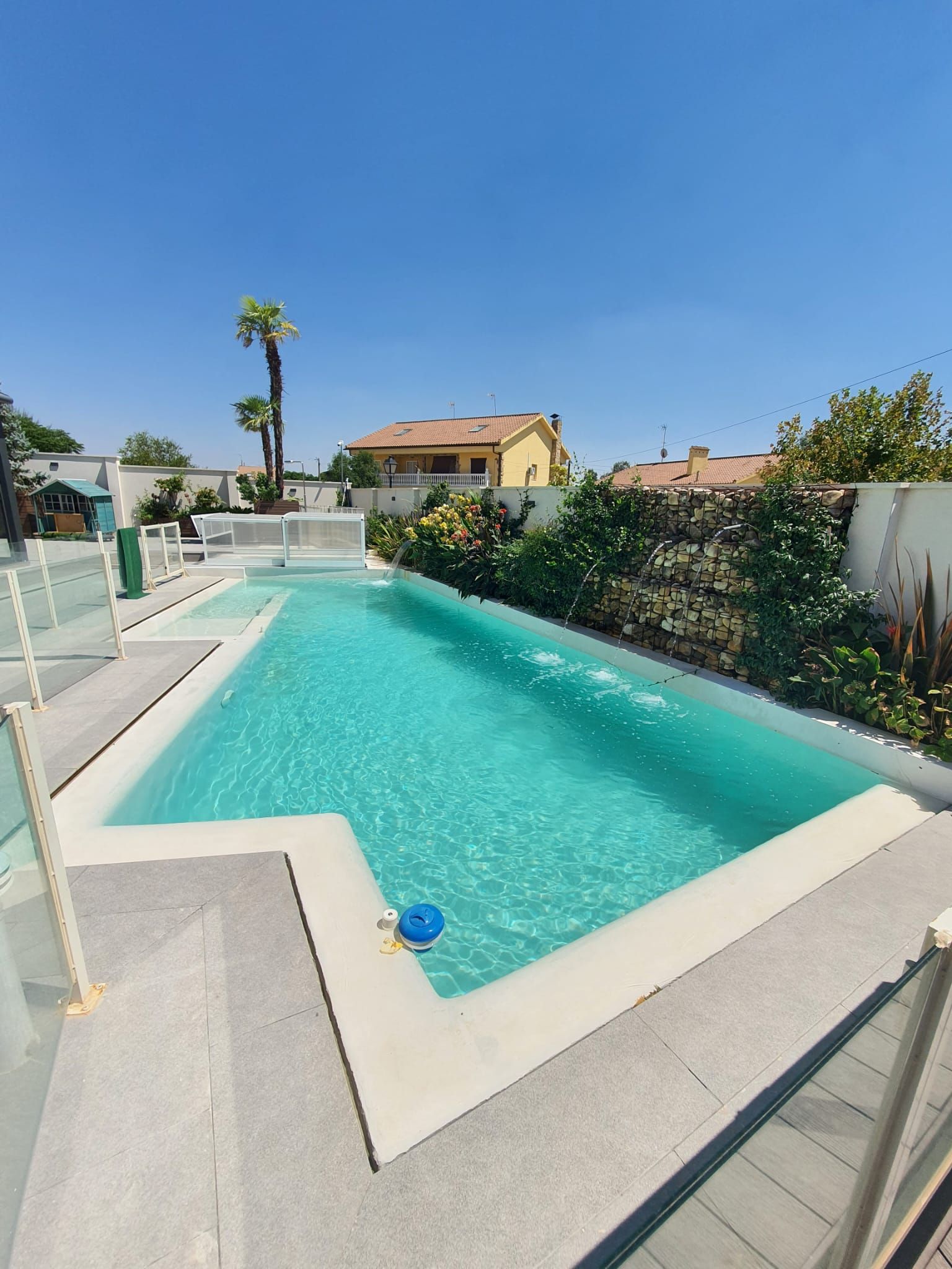 Piscina rectangular con agua turquesa clara en un día soleado.