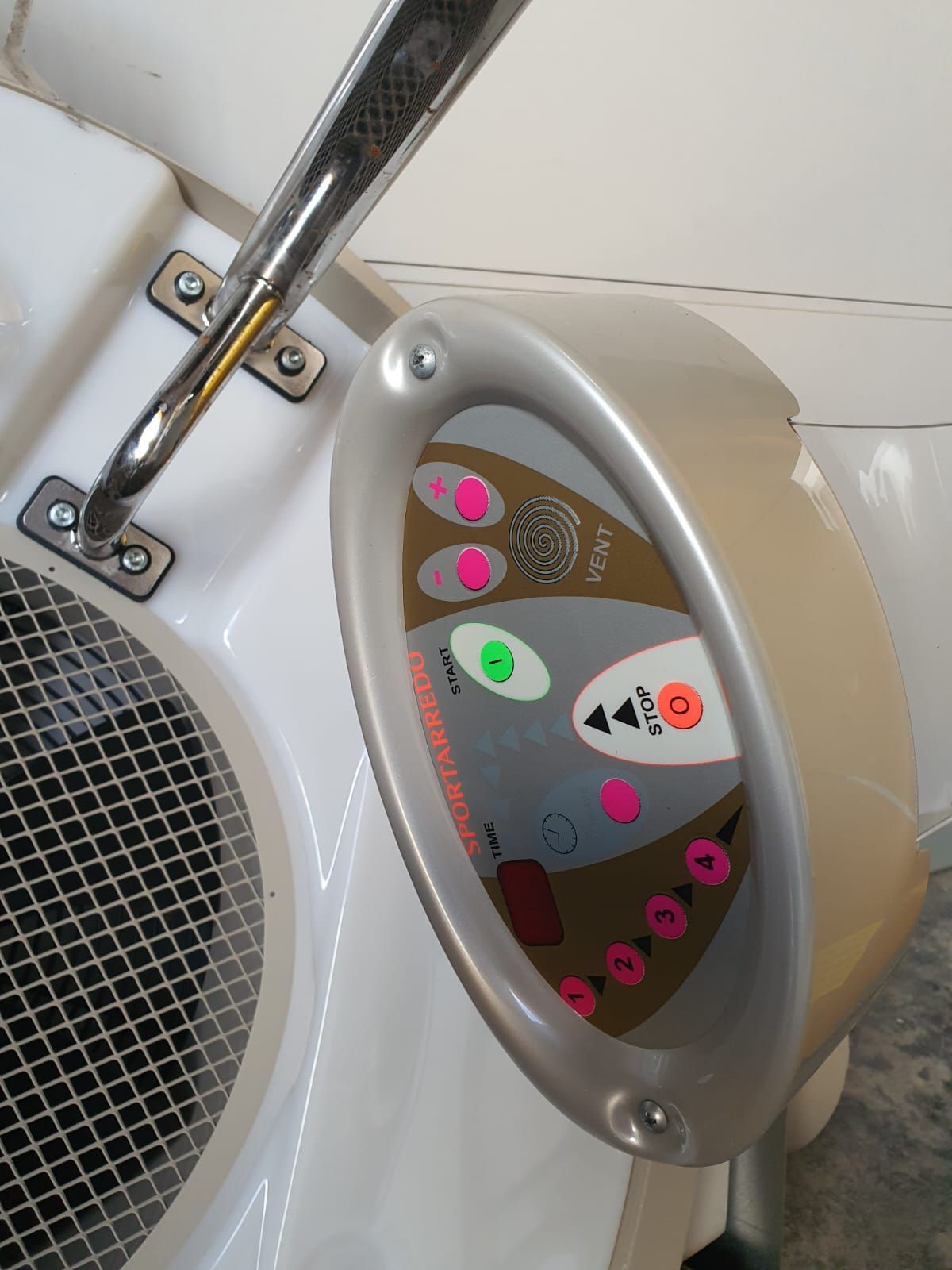 Panel de control blanco con botones: rosa, verde y naranja. Borde plateado y barra metálica. Rejilla en la parte inferior izquierda.