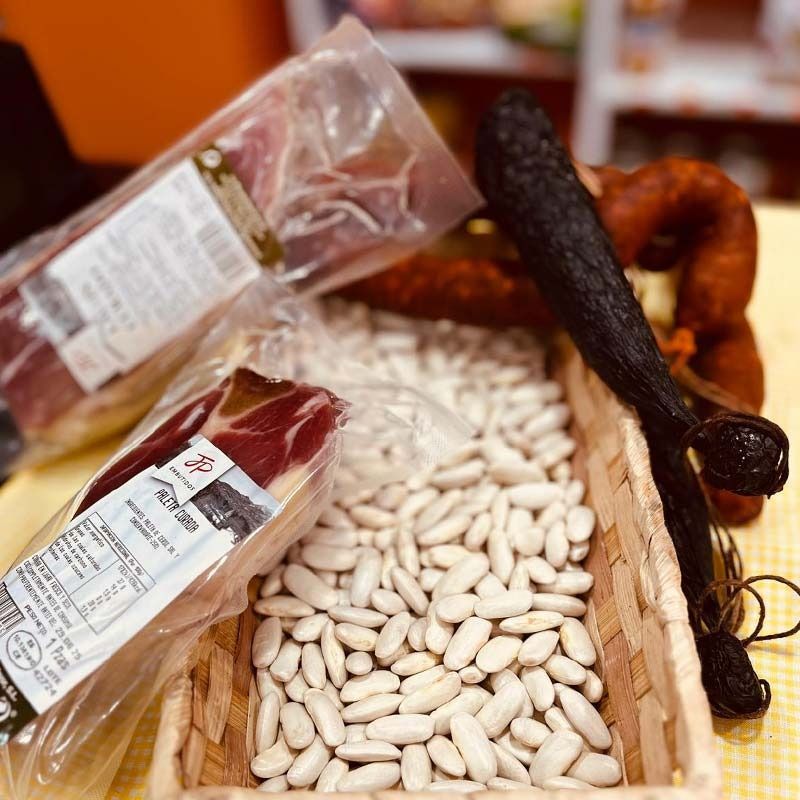 Una cesta llena de frijoles blancos junto a un paquete de carne.