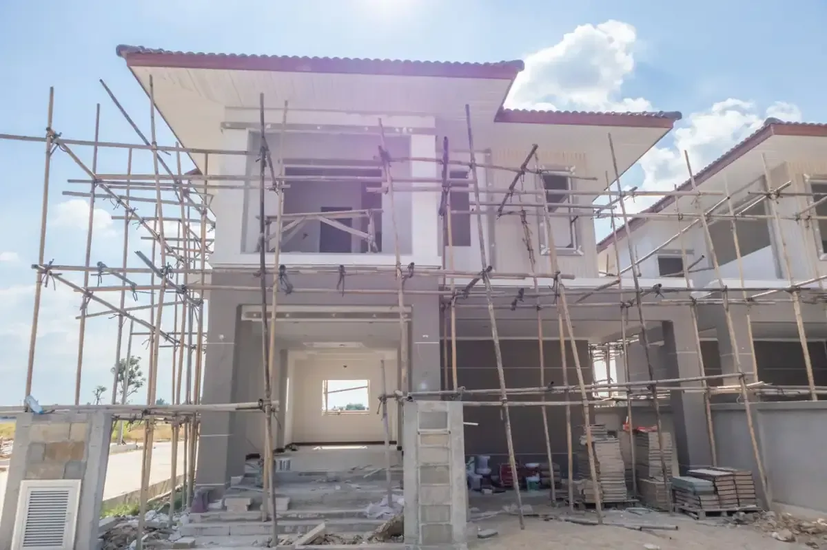 Casa en construcción con andamios contra un cielo azul.