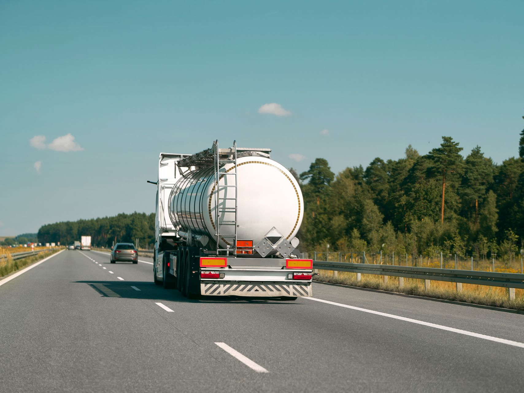 Camion-citerne circulant sur une autoroute, transportant un liquide ; journée ensoleillée.