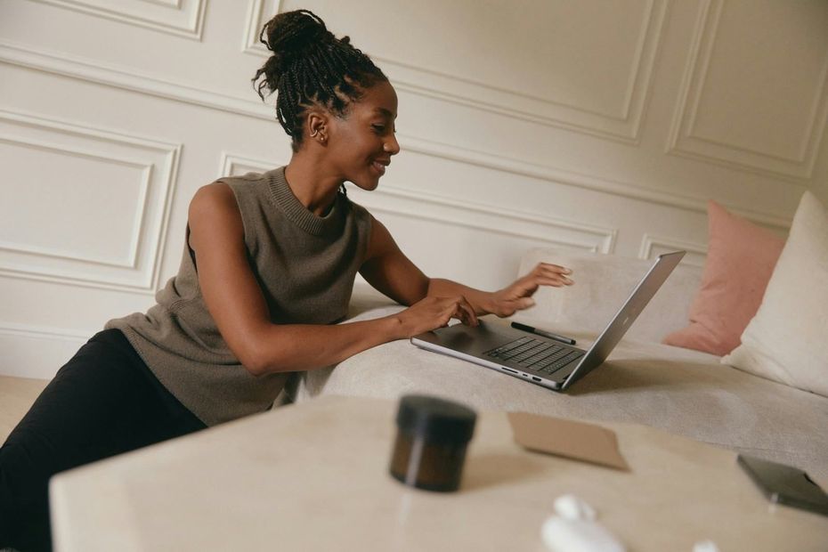 Person using a laptop on a bed in a bright room
