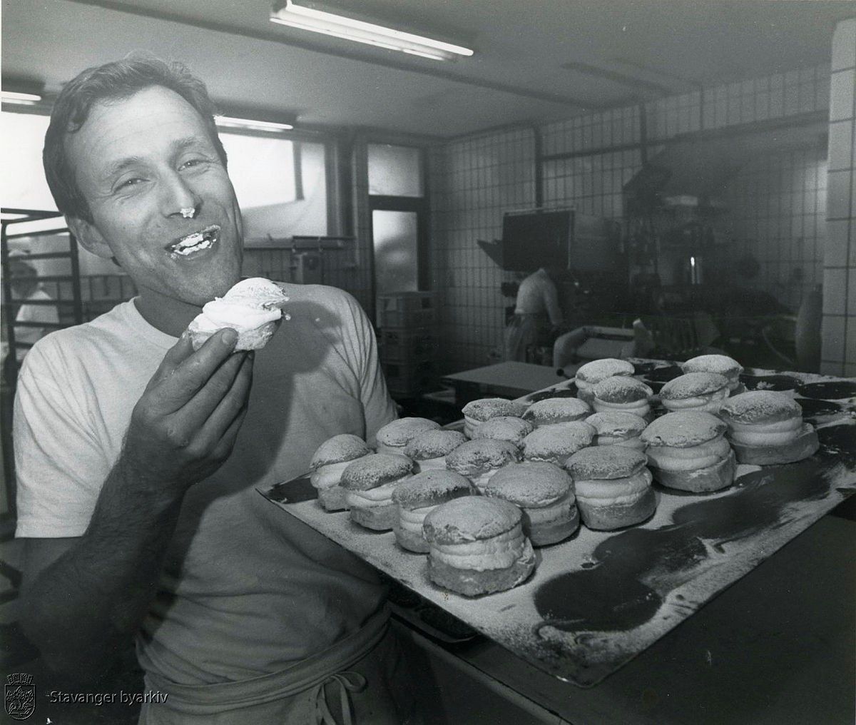 Finn Bjørner Romsøe tasting a cream bun beside a full tray in the bakery