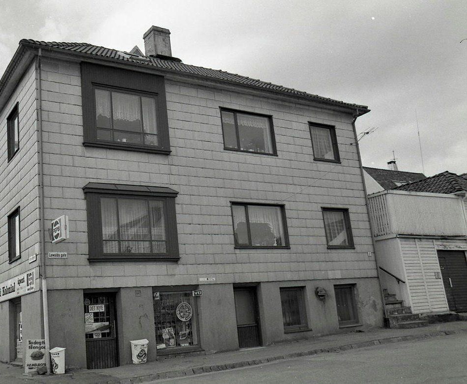 The wooden house next door, clad in panels, with a grocery shop on the corner