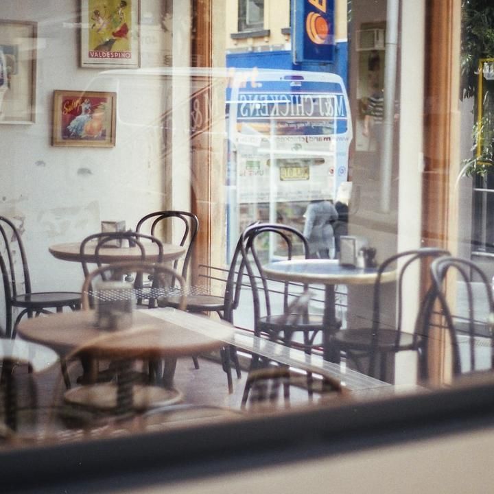 A café with bentwood chairs and round tables, seen through the window