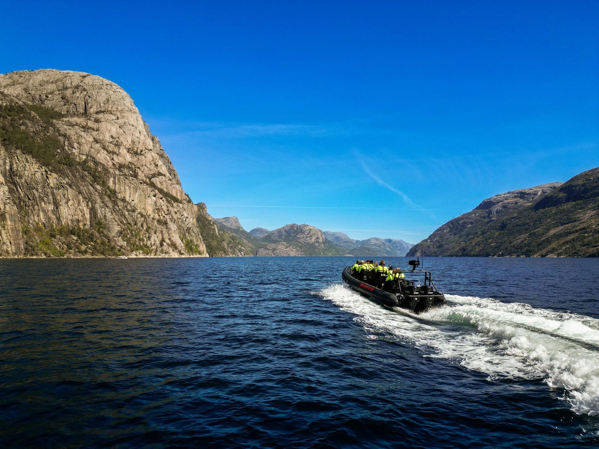 A RIB boat speeding through the fjord between steep mountains