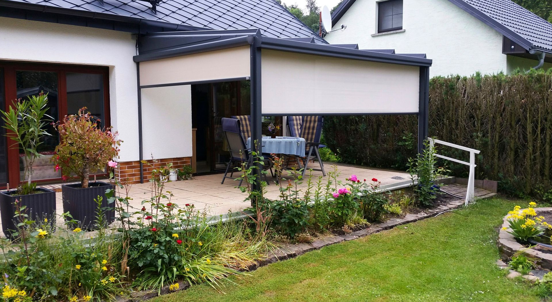 Terrasse mit einziehbarer Markise, Essbereich im Freien, Blumen und Grünpflanzen.
