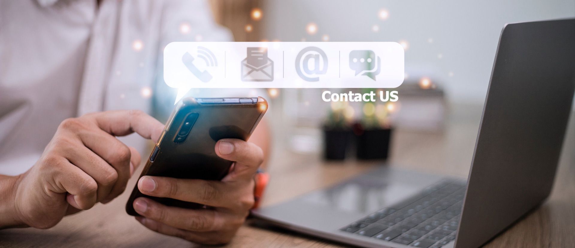 Una persona sostiene un teléfono celular frente a una computadora portátil.